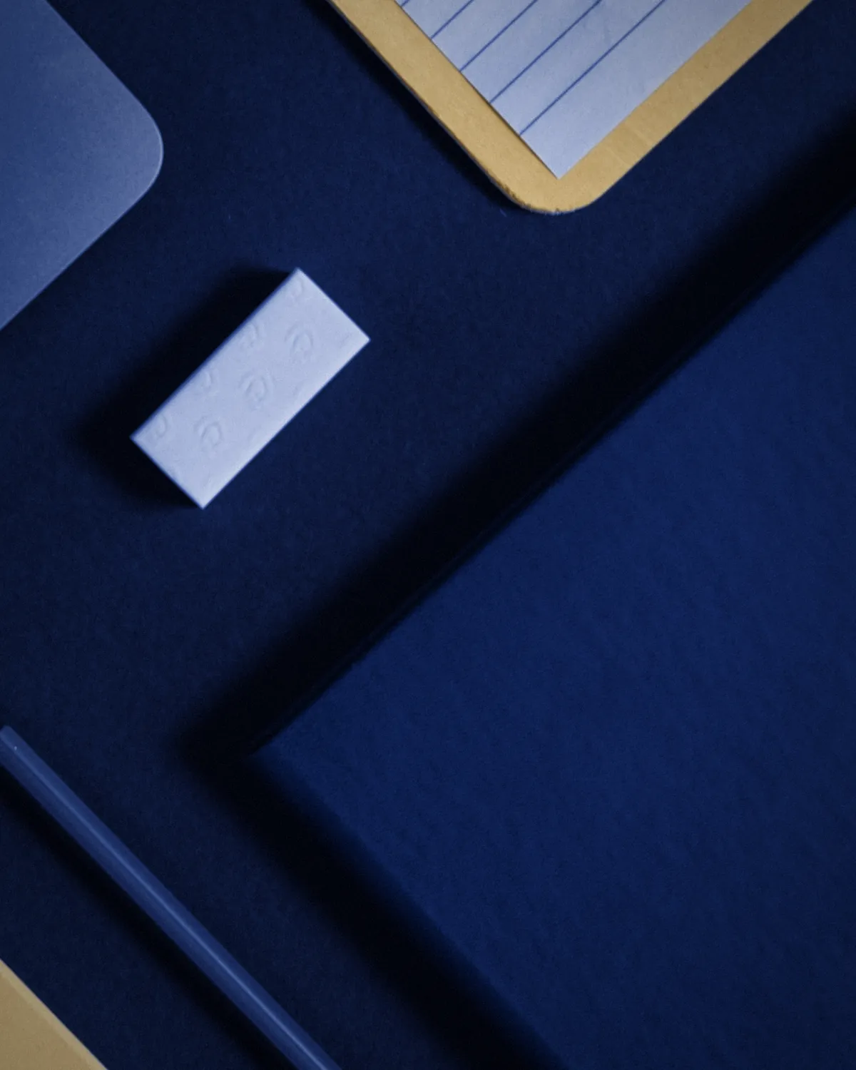 A navy desk flat lay with notebooks and a pencil